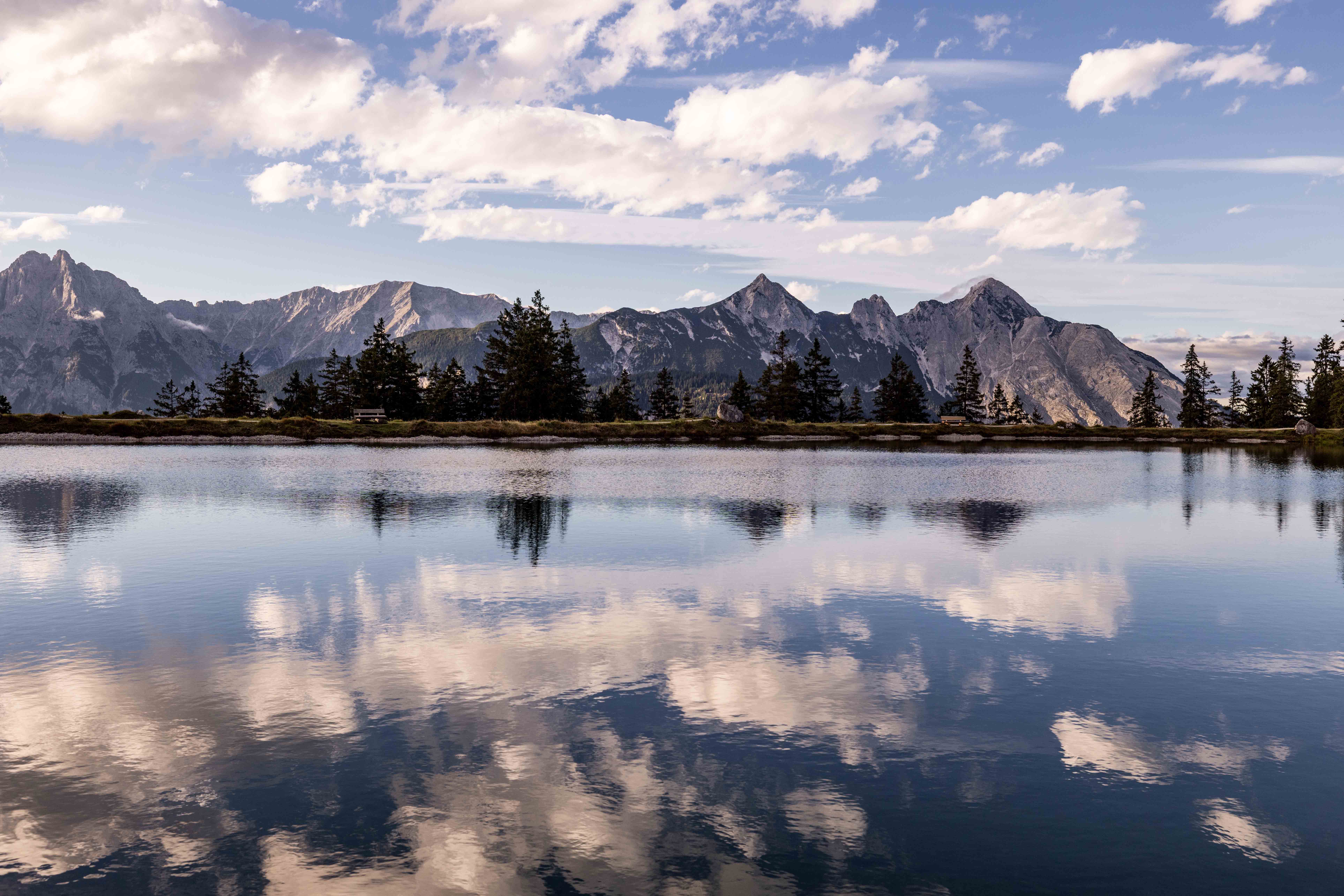 Ein Bergsee mit klarem Wasser, im Hintergrund Berge.