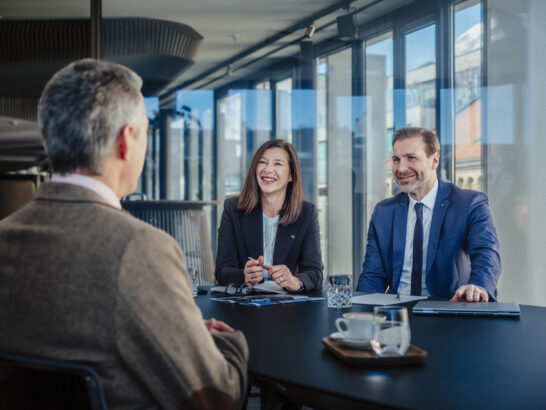 Zwei Berater der Hypo Tirol im Gespräch mit einem Kunden an einem Besprechungstisch