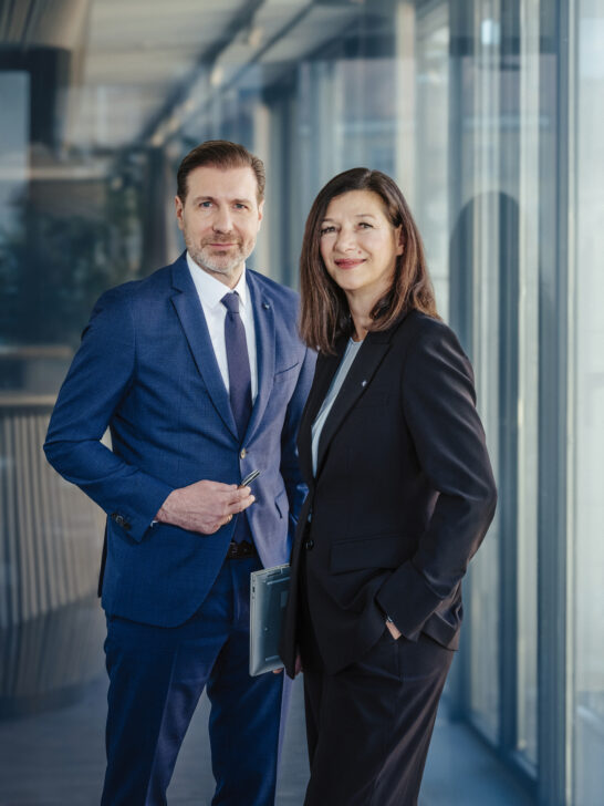 Berater und Beraterin der Hypo Tirol stehen gemeinsam im Büro – Symbol für Dualbetreuung