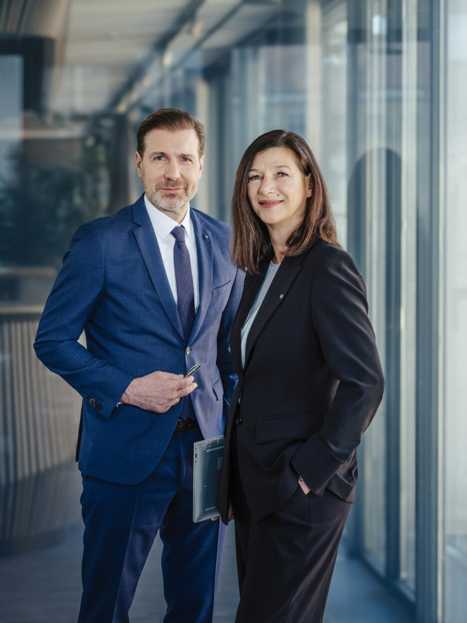 Berater und Beraterin der Hypo Tirol stehen gemeinsam im Büro – Symbol für Dualbetreuung