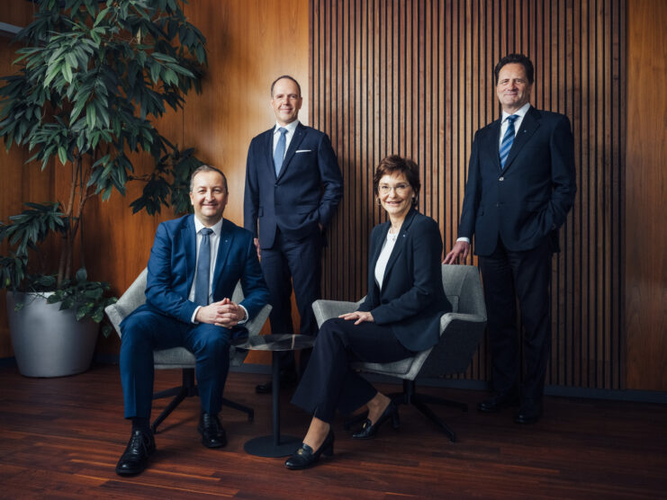 Vorstände und Aufsichtsratvorsitzender der Hypo Tirol posieren zusammen. Der Hintergrund ist eine Holztäfelung, links steht eine Pflanze.